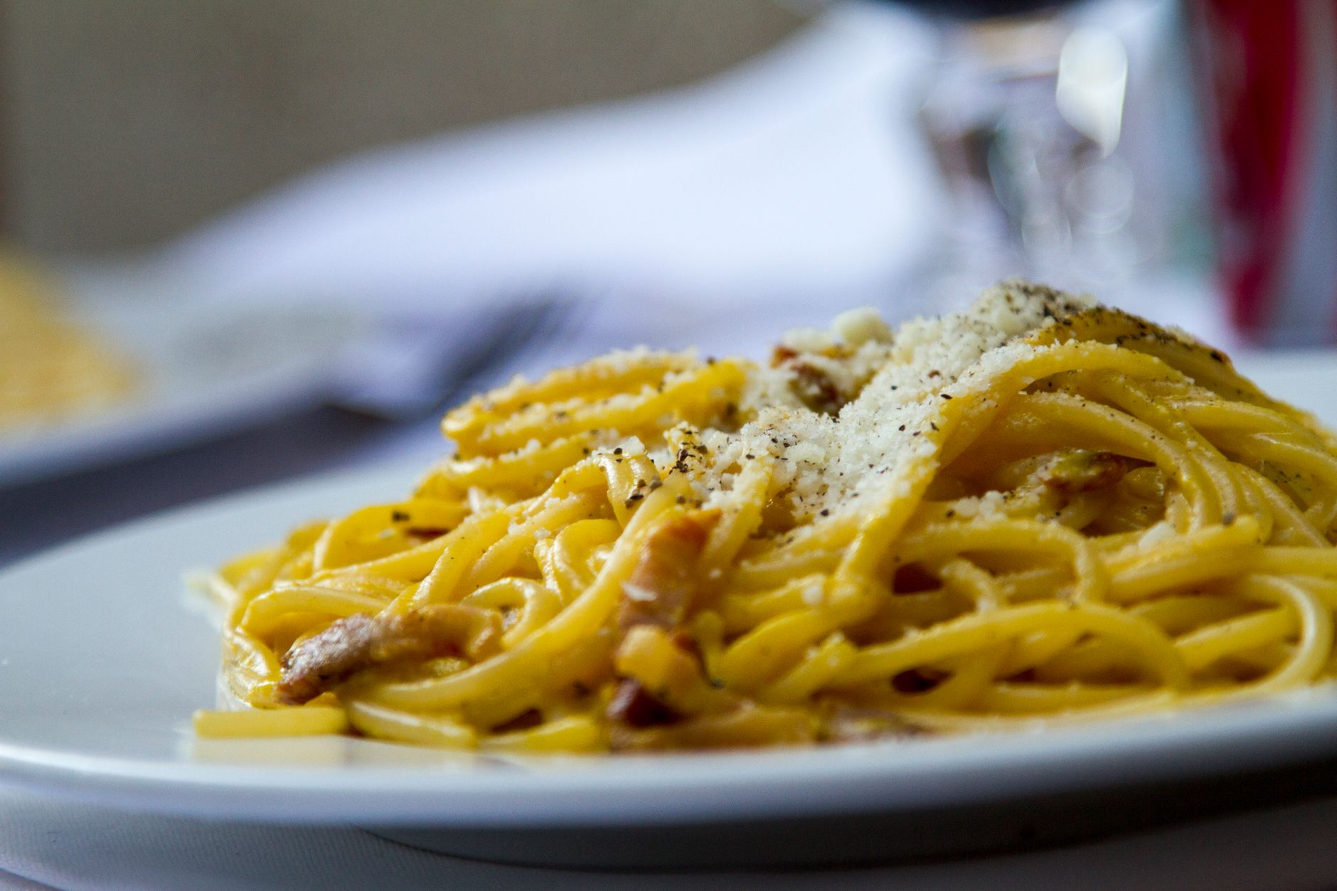 Zbliżenie na spaghetti carbonara z tartym parmezanem na talerzu